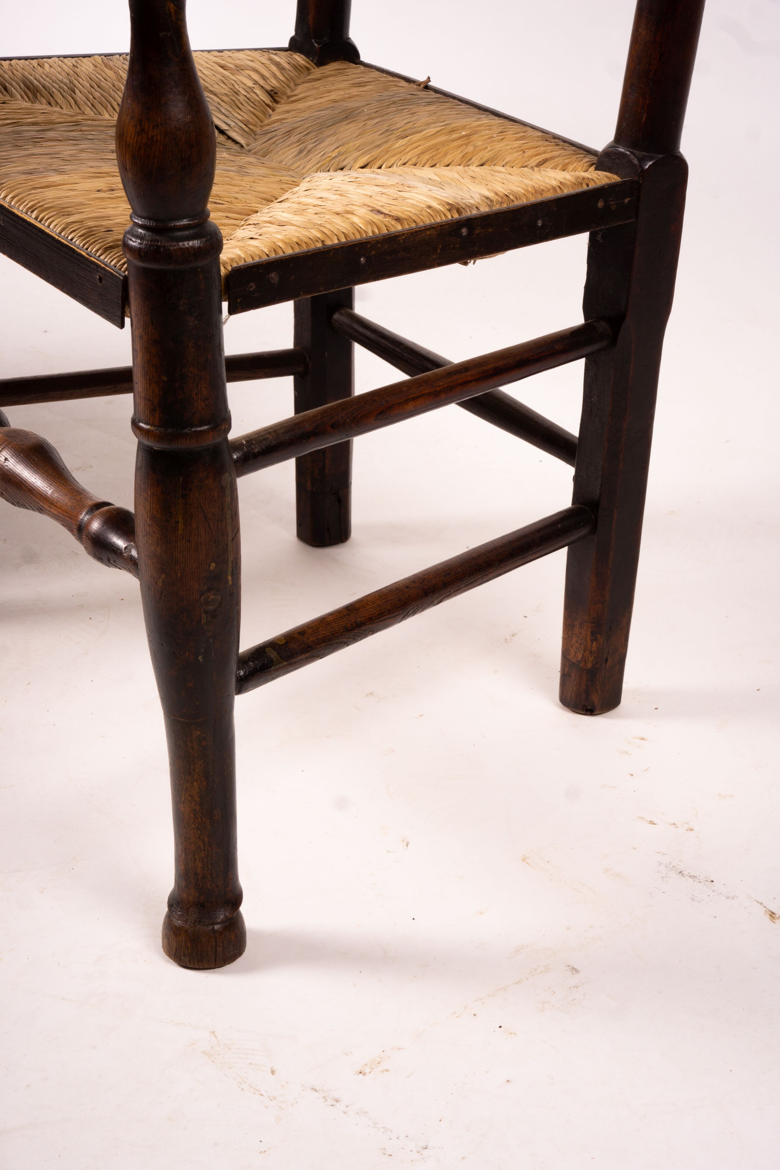 A pair of early 19th century Lancashire ash and fruitwood rush seat ladderback elbow chairs, width 60cm, depth 46cm, height 110cm